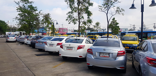 Chiang Mai,Thailand - January 28, 2024: Many cars parked for rent, taxi and buses for pick up passengers on parking near airport. Travel, vehicle and Transportation.