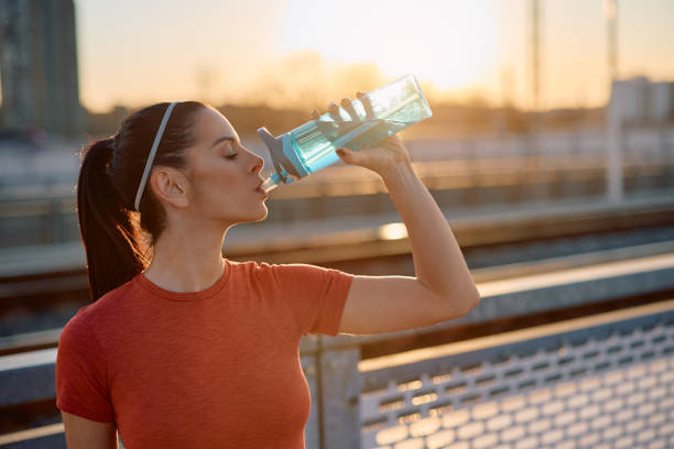 istock Young athletic woman drinking water at sunset. 2067798566