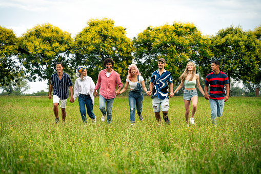 Group of multiethnic teenagers spending time outdoor on a picnic at the park. Concept about generation z, lifestyle and friendship