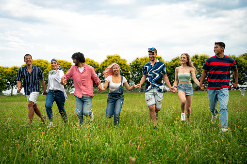 Group of multiethnic teenagers spending time outdoor on a picnic at the park. Concept about generation z, lifestyle and friendship