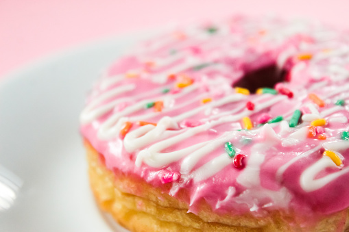 close up of a pink donut with colorful sprinkles on top