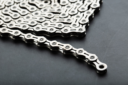 Silver chain of a road bike on a dark textured background with free space