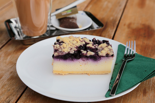 blueberry cheesecake on a white platte on a wooden table