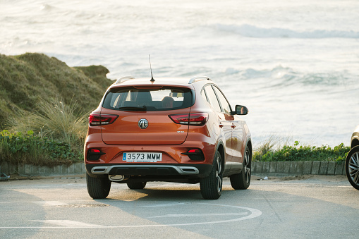 Tagle, Spain - 6 March 2024: An orange MG ZS car parked by the sea