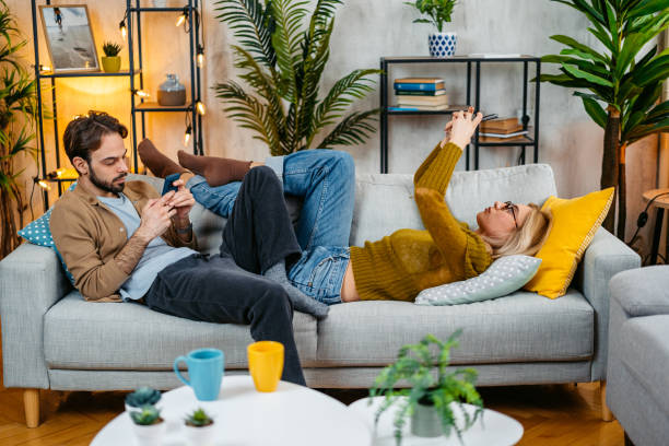 istock Young Couple Using Their Phones On The Sofa 2067880555