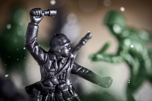 Toy soldier fighting in battle, sugar and coffee used to simulate snow, soil and explosions