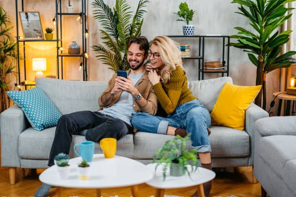 istock Young Couple Using A Phone Together On The Sofa 2067887451