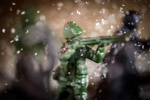 Toy soldier fighting in battle, sugar and coffee used to simulate snow, soil and explosions