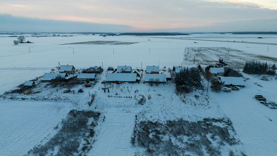 Drone photography of small villager in the middle of meadows during winter cloudy morning