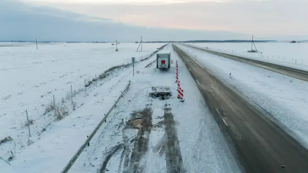 Photo of Drone photography of lorry accident site, abandoned trailer and burned up asphalt in a highway during winter morning