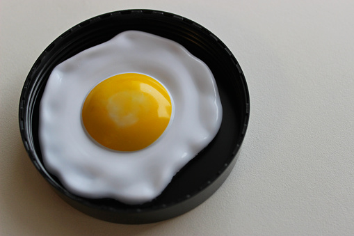 Eggs cracked into a bowl in preparation for cooking.  An egg carton with eggs is visible in the background.
