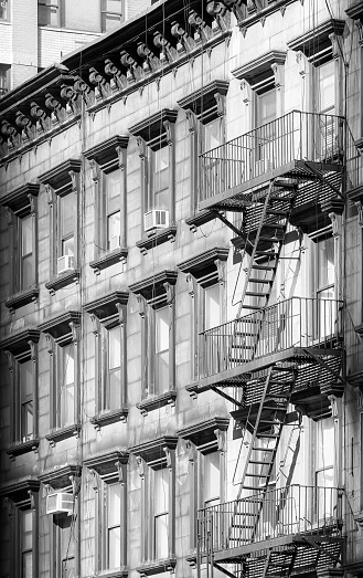 Black and white photo of an old building with fire escape, New York City, USA.