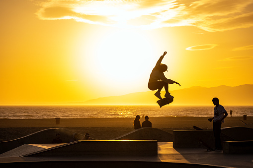 Los Angeles, United States - April 20th, 2023: A skater in Venice Beach performs a jump in front of the setting sun