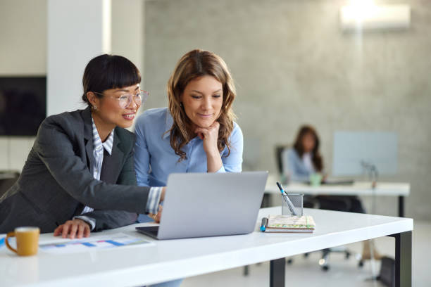 Happy diverse businesswomen working on laptop in the office. Happy female entrepreneur cooperating while reading an e-mail on a computer in the office. Copy space. asian female engineer stock pictures, royalty-free photos & images