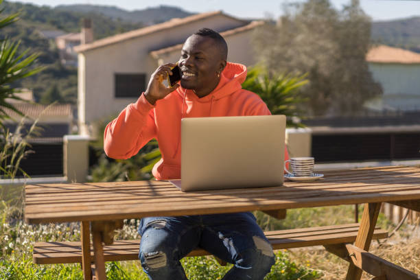 freelancer negro falando no smartphone - internet computer monitor discussion surfing the net - fotografias e filmes do acervo
