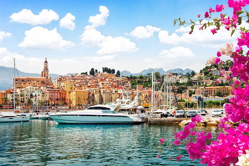colorful houses of Menton old town harbor at summer day, France, with flowers