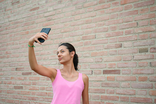 young woman on her fitness journey as she pauses to capture a candid selfie before diving into her workout routine.