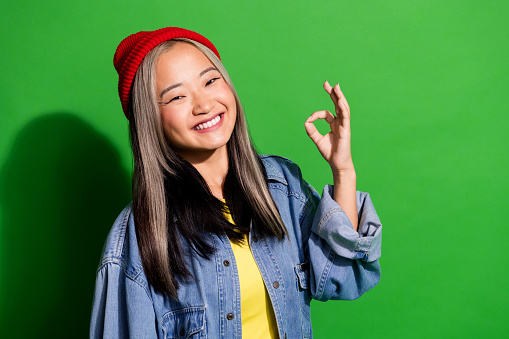 Photo of cheerful positive lady wear denim jacket smiling showing okey sign isolated green color background.