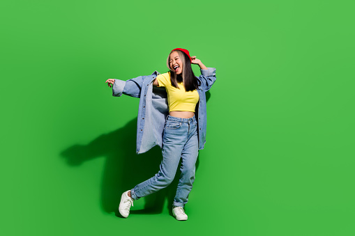 Full length photo of carefree cheerful lady wear denim jacket having disco fun empty space isolated green color background.