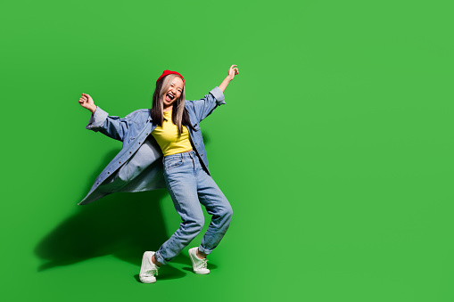 Full length photo of pretty funky lady wear denim jacket dancing disco empty space isolated green color background.