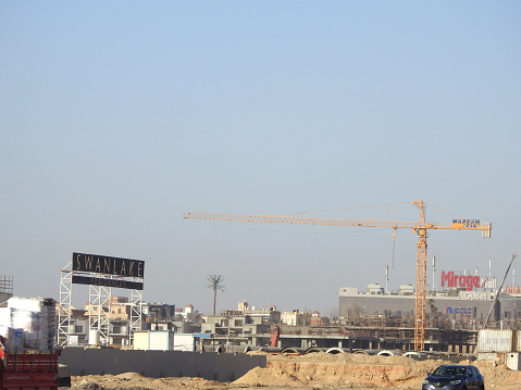 Cairo, Egypt, March 2 2024: A crane tower of Hassan Allam Co, A construction site of new high rise with cranes to transport heaving objects, new real estate projects in Egypt, selective focus