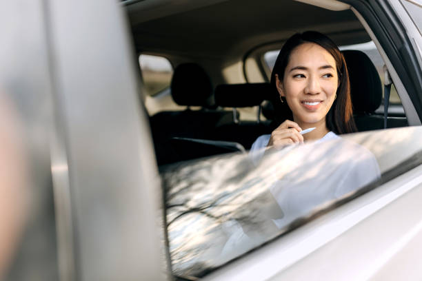 istock Smiling beautiful woman working while sitting on a backseat of car 2068081292