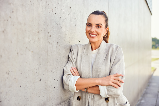 Portrait of beautiful businesswoman leaning against concrete wall