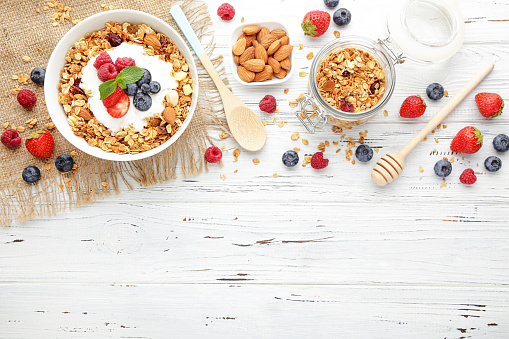 Tasty granola with fresh berries on white wooden background