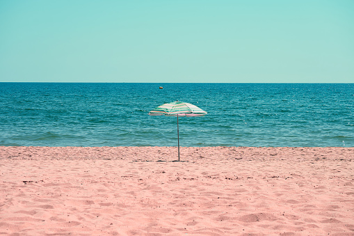 Lonely beach umbrella on the sand. Minimalist seascape. Paradise place.