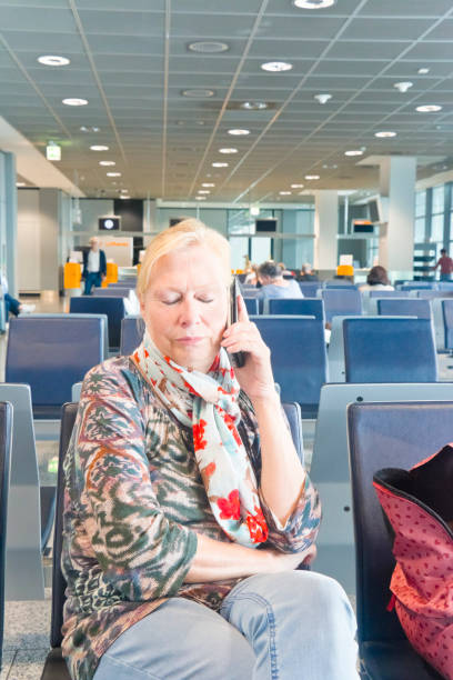 mulher infeliz usando o telefone móvel em um lobby do aeroporto - stranded travel people traveling disappointment - fotografias e filmes do acervo