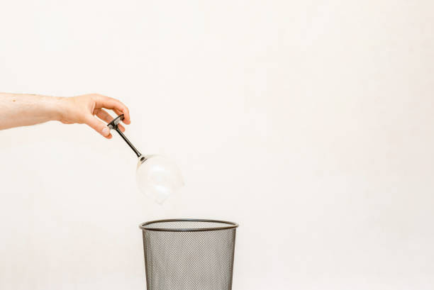 a glass of wine is thrown into the trash,can for disposal and recycling.white,gray background,selective focus,copy space. - 11270 stock-fotos und bilder