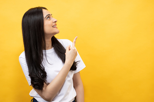 Portrait of young girl wearing white t-shirt on yellow background