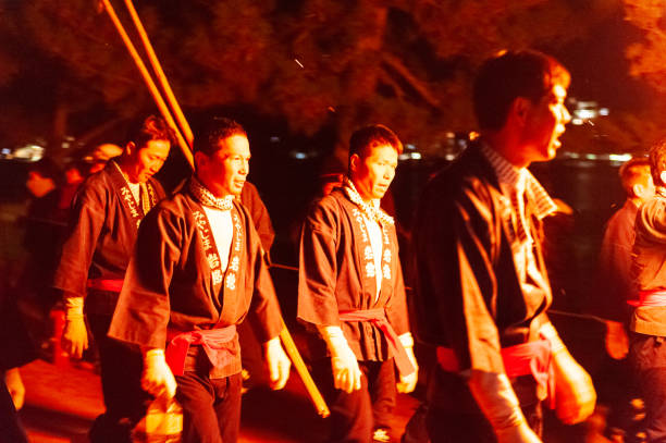 Miyajima, Japan â December 31, 2019. Participants of the Chinkasai Fire Festival at Itsukushima Shrine, near Hiroshima, carry large burning torches around the sea shore as part of a ritual to safeguard the island from fires.