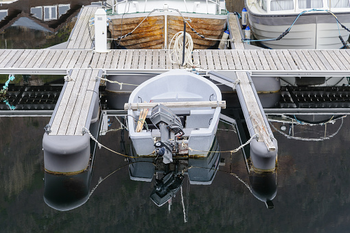 A top-down view of a single motorboat tied to a serene, empty dock, surrounded by still waters.