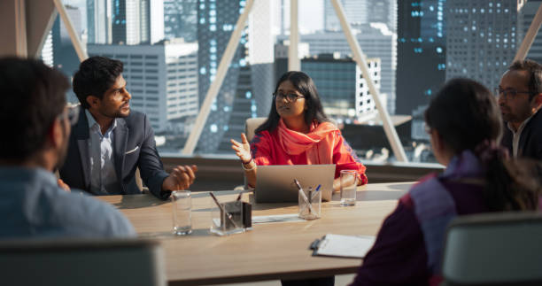 istock Indian Female Project Manager Makes a Business Presentation for a Diverse Creative Team in a Meeting Room in an Agency. South Asian Colleagues Gathered Around a Conference Table, Talking. 2068231202