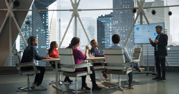 istock Modern South Asian Business Office Meeting: Confident Indian Manager Uses Interactive Display, Makes Report to a Group of Corporate Partners, Shows Statistics, Growth and Financial Analytics 2068232255