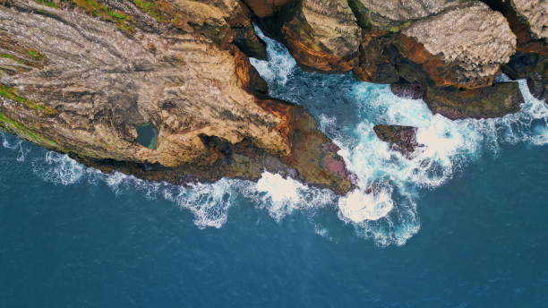 istock Foaming waves crashing rocky cliffs top view. Drone shot of dramatic coastline 2068232767