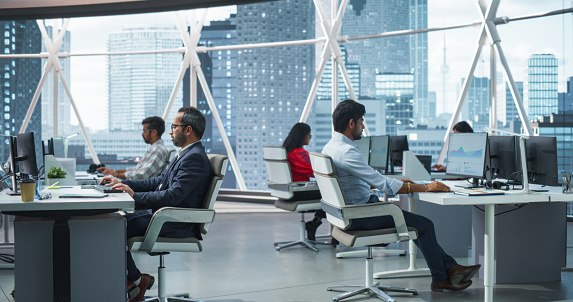 Team of Talented Young Indian Professionals Working in Corporate Hedge Fund. Financial Analysts and Managers Working on Computers in a South Asian Business Office with Scenic City View