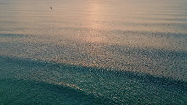 Majestic ocean surface rippling under evening sunlight aerial. Golden sunset