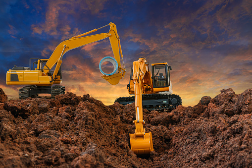 Crawler Excavators are digging the soil in the construction site on the sunset sky backgrounds