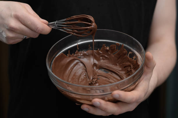 istock Bowl with liquid shiny chocolate icing close-up in hands 2068245862