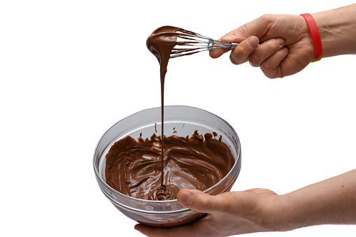 Melted chocolate in a bowl on a white background, tempering the chocolate