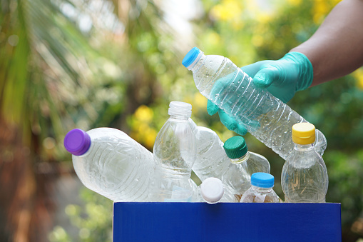 Hand holds plastic bottle to put in junk bin for recycling. Concept, sorting garbage campaign before throw away for reuse or recycle. Environment conservation. Eco friendly activity.