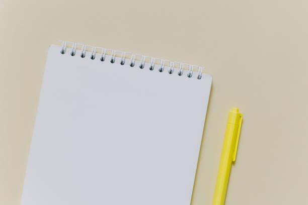 istock Notebook with blank page and yellow pen on light yellow background. 2068258016