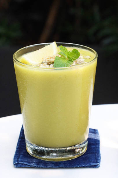 Stock photo showing close-up view of drinking glass filled with ice cubes and containing avocado, spinach and kiwi juice smoothie as part of a healthy breakfast.