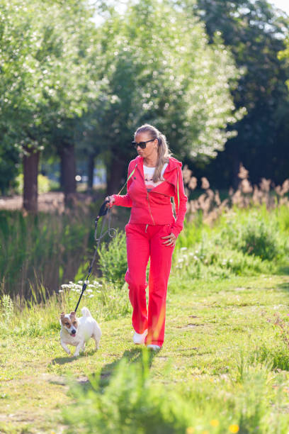 Leasure walk with dog Woman in casual red jogging suit walking in nature with dog during Spring leasure games stock pictures, royalty-free photos & images