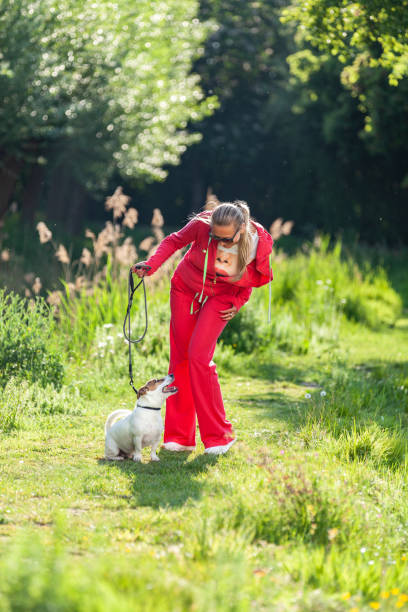Leasure walk with dog Woman in casual red jogging suit walking in nature with dog during Spring leasure games stock pictures, royalty-free photos & images