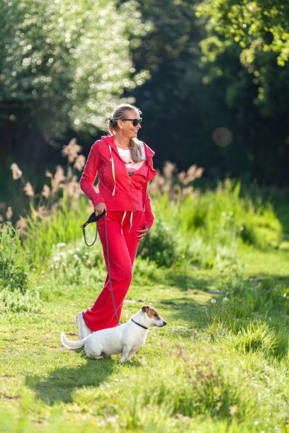 Leasure walk with dog Woman in casual red jogging suit walking in nature with dog during Spring leasure games stock pictures, royalty-free photos & images