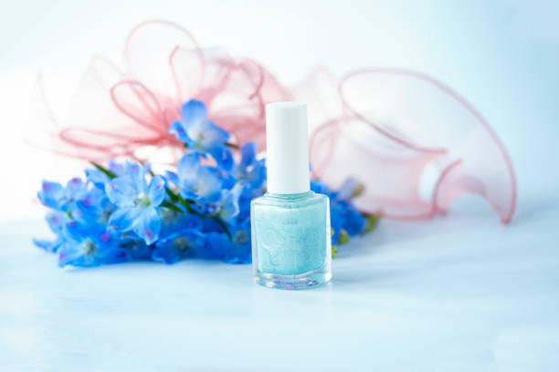 青い花「デルフィニウム」の花束と化粧品。青い背景で。/ ブルーネイルポリッシュ