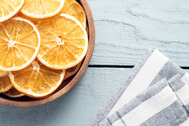 Dry orange slices in plate on wooden background